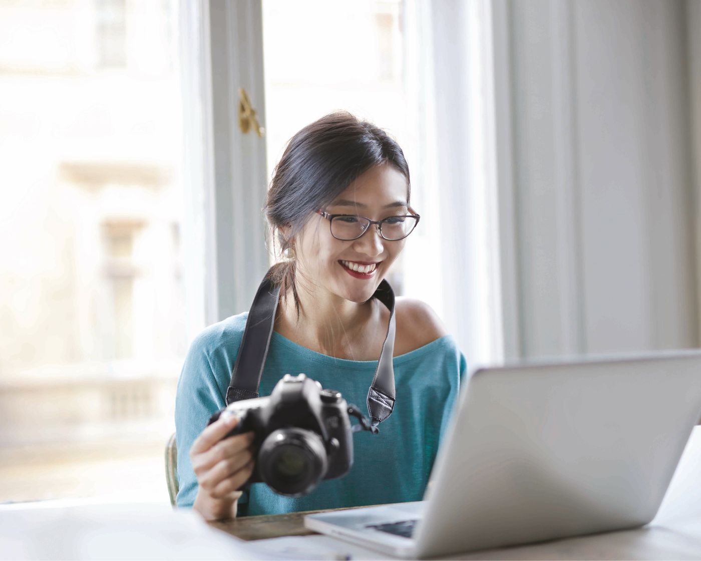 Woman in progressive lenses reviewing photos on a laptop by a window