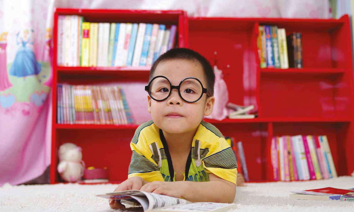 Young boy in round glasses reading a book, wearing Kids MYO lenses